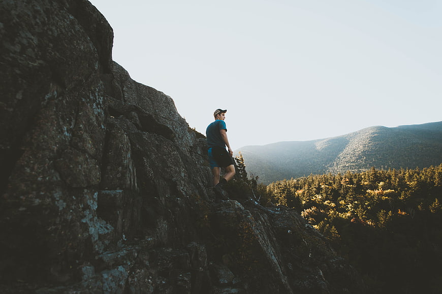 Man hiking on rocky mountain ridge overlooking forest