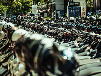 Rows of parked motorcycles with helmets in urban street