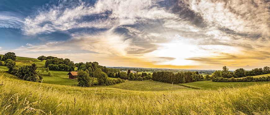 Panoramic Summer Meadow Landscape With Wooden Barn And Dramatic Sunset Sky