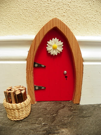 Miniature red fairy door with daisy and firewood basket