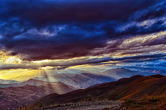 Dramatic mountain landscape with sun rays breaking through clouds