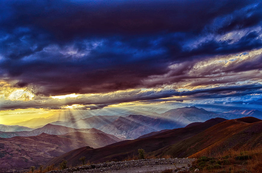 Dramatic mountain landscape with sun rays breaking through clouds