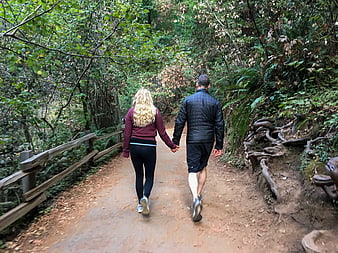 Couple holding hands hiking on forest trail
