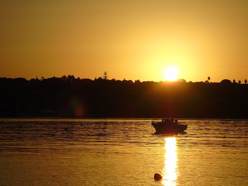 Silhouette of boat on calm sea at golden sunset