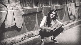 Woman Crouching in Urban Street with Graffiti Background