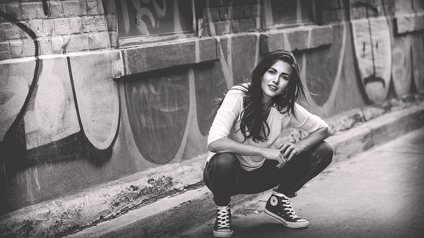 Woman Crouching in Urban Street with Graffiti Background