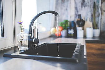Modern black kitchen sink with running water and flower