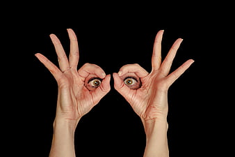 Hands forming circles with eyes looking through black background