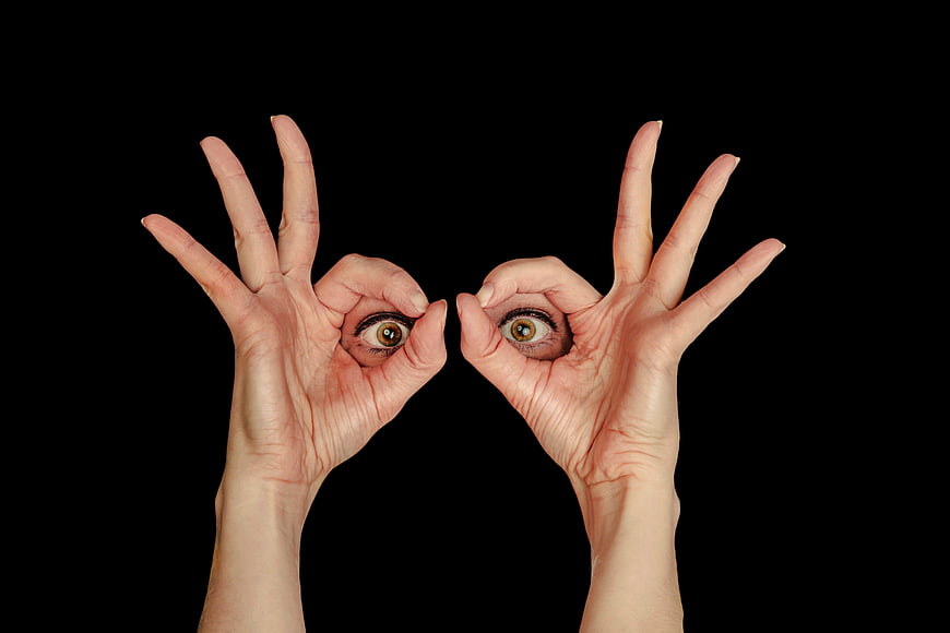 Hands forming circles with eyes looking through black background