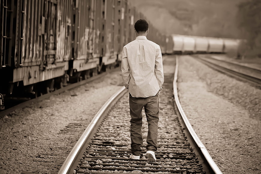 Man Walking Away on Train Tracks in Sepia Tone