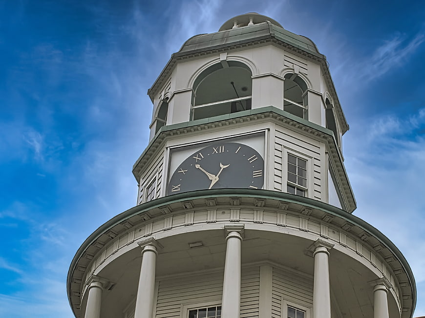 Low angle view of white clock tower against blue sky