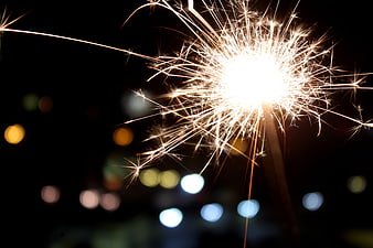 Bright Sparkler Burning at Night with Bokeh Background