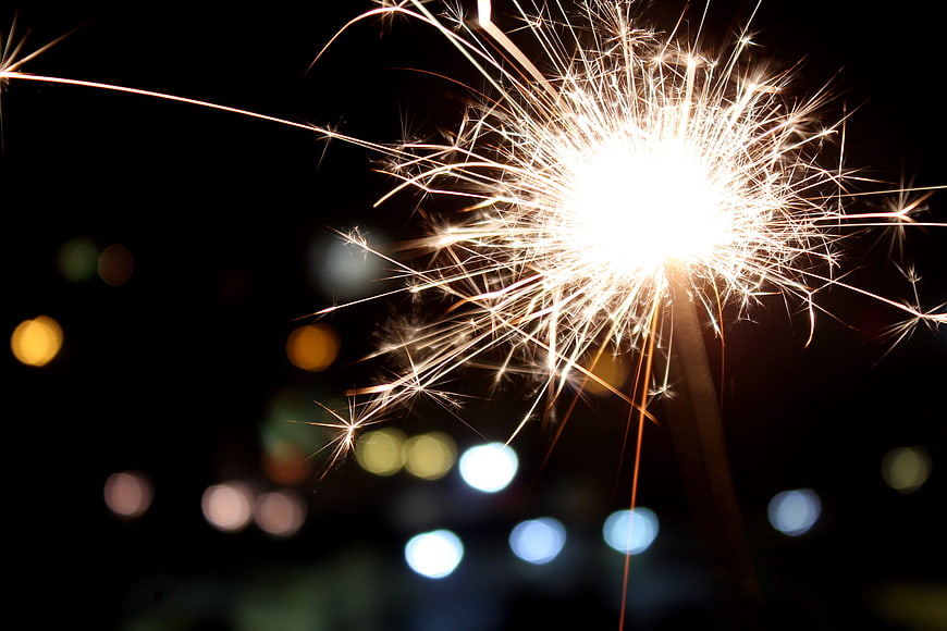 Bright Sparkler Burning at Night with Bokeh Background
