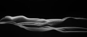 Monochromatic abstract nude figure lying on dark textured surface