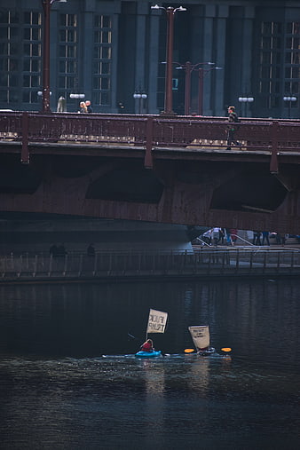 Kayakers with protest signs on river under city bridge