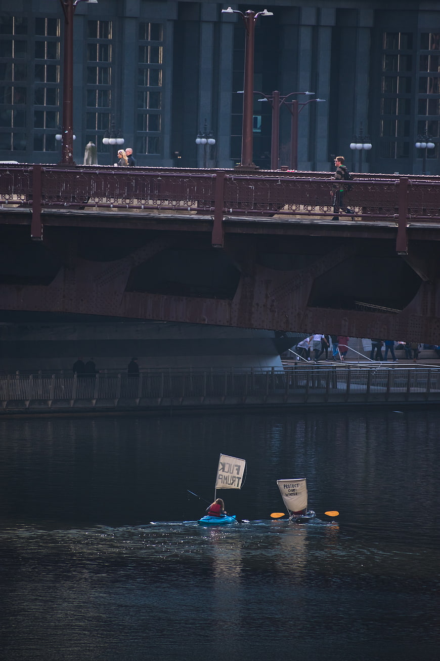 Kayakers with protest signs on river under city bridge