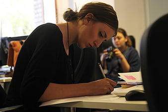 Young woman writing at desk in modern office workspace
