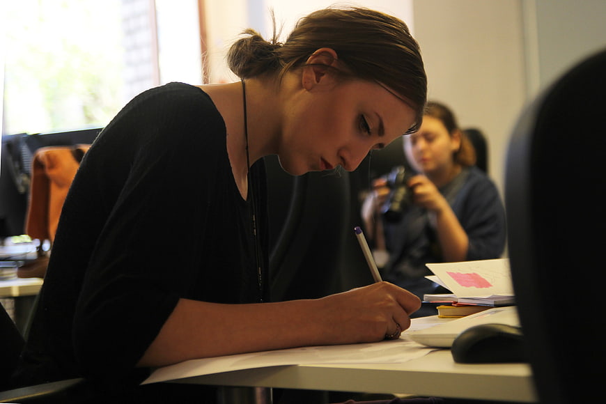 Young woman writing at desk in modern office workspace