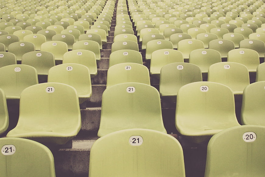 Rows of empty green stadium seats with numbers
