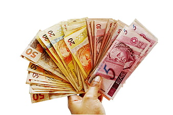 Hand holding fan of Brazilian Real banknotes on white background