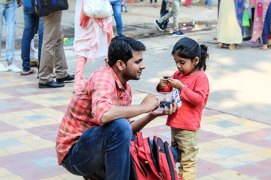 Father feeding daughter berries on colorful tiled street