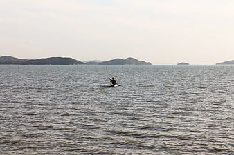 Lone Kayaker Paddling in Calm Coastal Waters with Islands