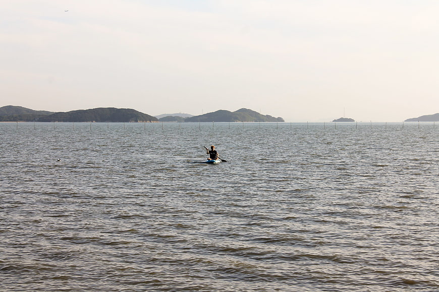 Lone Kayaker Paddling in Calm Coastal Waters with Islands