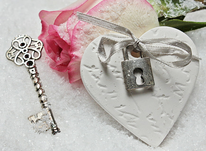 Vintage key and padlock on heart with pink rose in snow