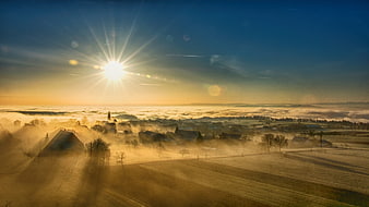 Sunrise over a foggy village with golden light and misty fields
