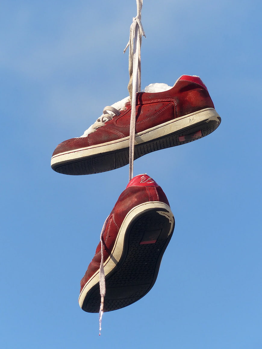 Red Sneakers Hanging on Power Lines Against Blue Sky