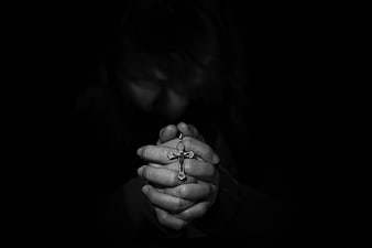 Woman praying with rosary in dark