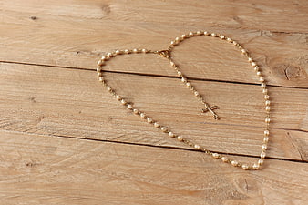 Gold Pearl Rosary Necklace on Wooden Background