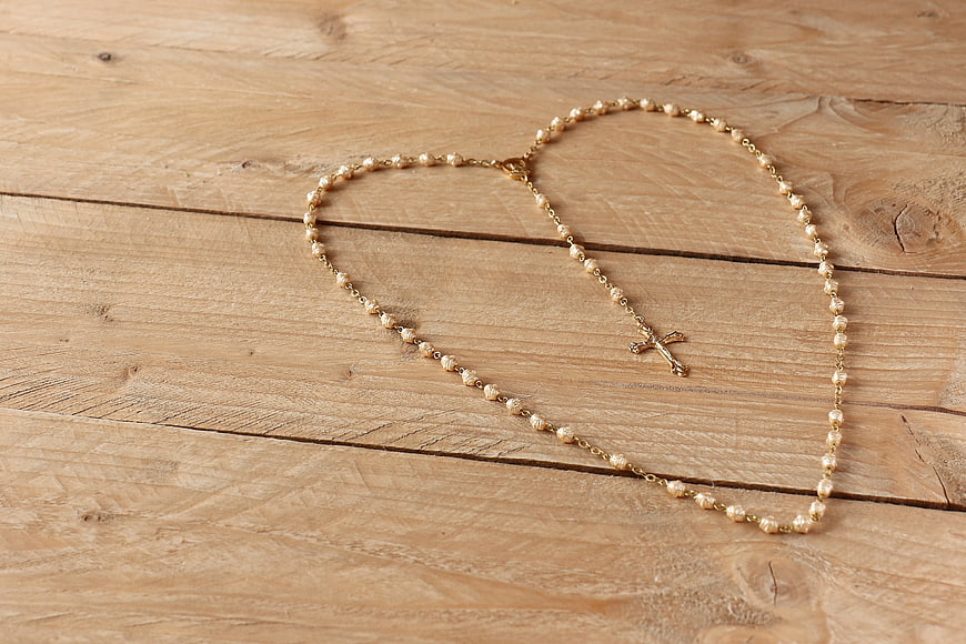 Gold Pearl Rosary Necklace on Wooden Background