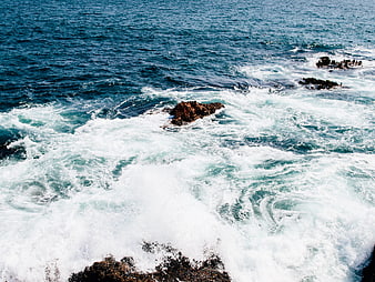 Aerial view of crashing ocean waves against rocky coastline