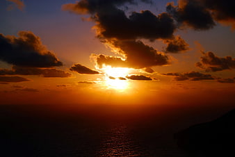 Dramatic Sunset Over Ocean with Golden Sunlight and Clouds