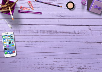 Purple flat lay with smartphone, makeup, and stationery on wooden background