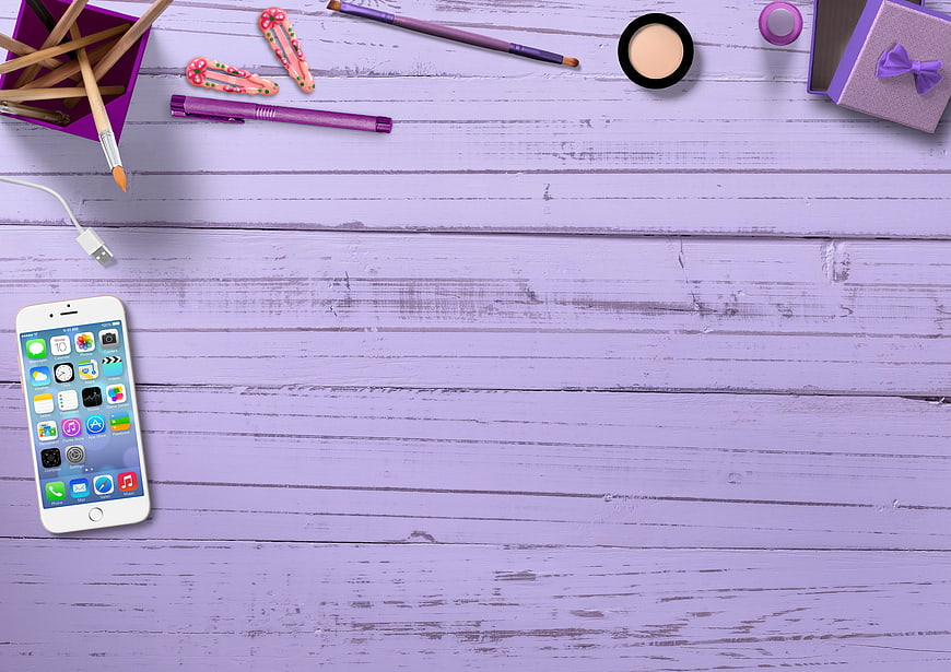 Purple flat lay with smartphone, makeup, and stationery on wooden background