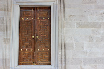 Ornate wooden door with geometric patterns in stone wall