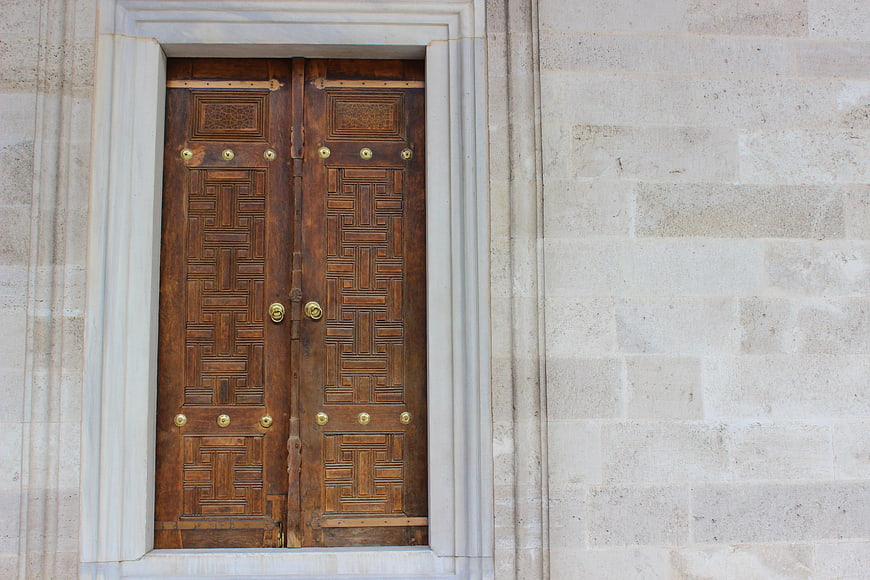 Ornate wooden door with geometric patterns in stone wall