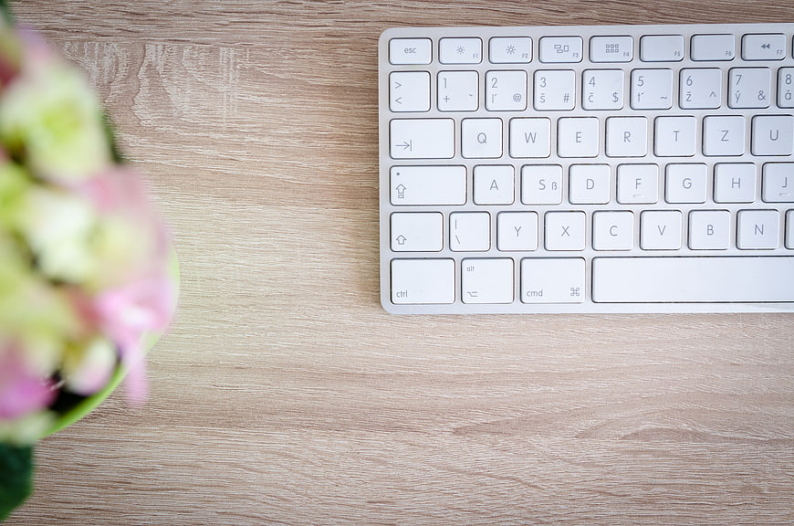 White Keyboard on Wooden Desk with Pink Flowers