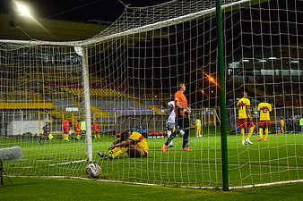 Soccer players sitting on field behind goal net at night