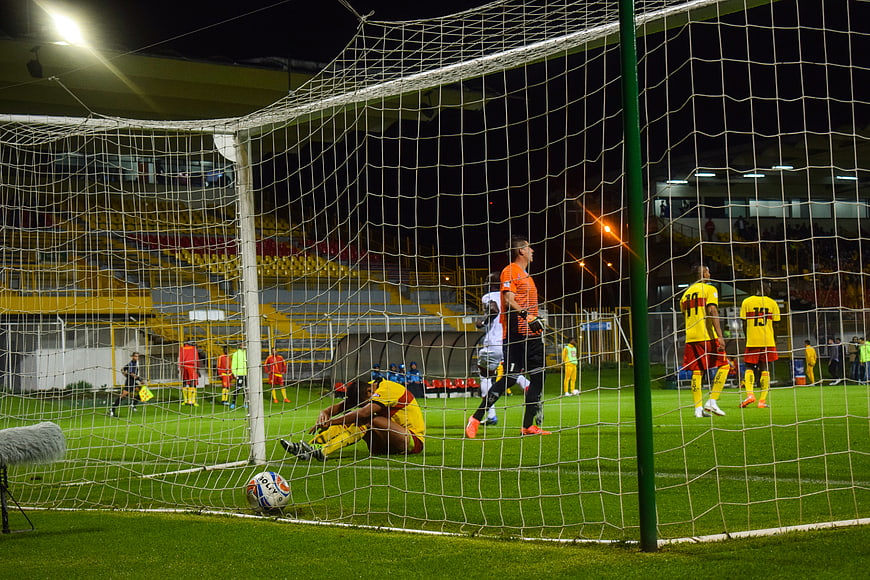 Soccer players sitting on field behind goal net at night