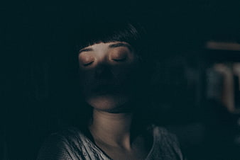 Dark moody portrait of woman with closed eyes in shadow