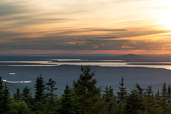 Scenic Sunset Over Forested Lakes and Distant Mountains