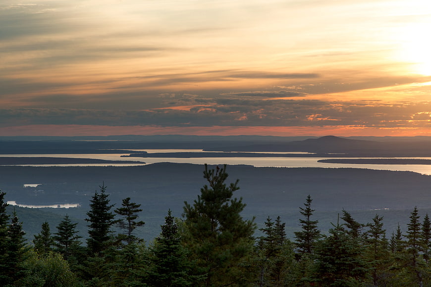 Scenic Sunset Over Forested Lakes and Distant Mountains