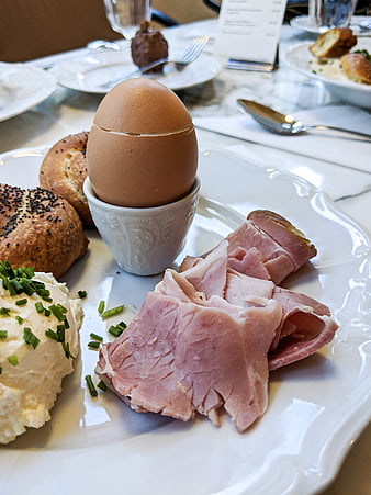 Traditional breakfast plate with soft boiled egg, ham, and bread