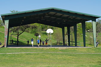 Men playing basketball under park pavilion