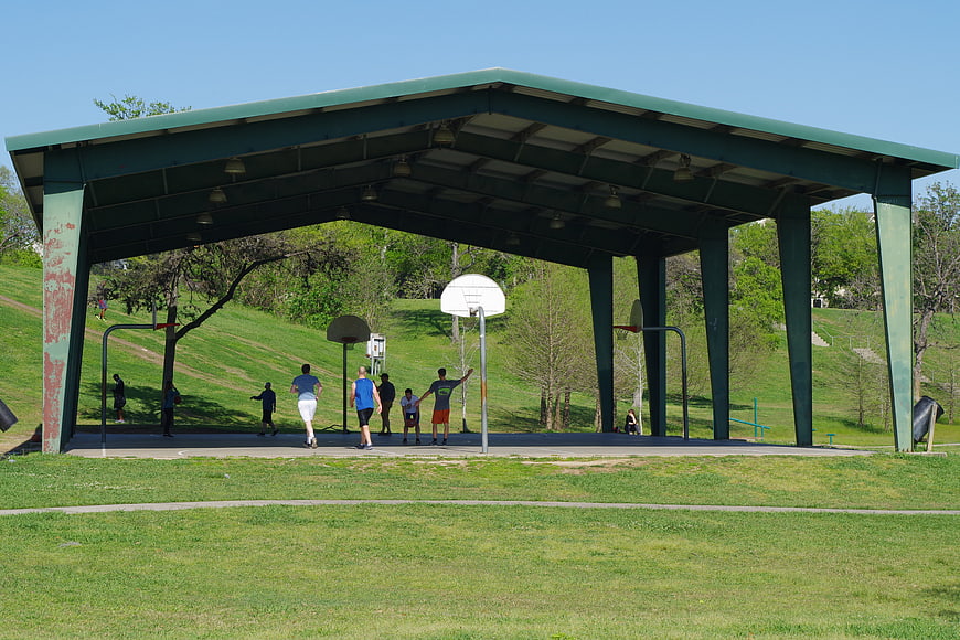 Men playing basketball under park pavilion