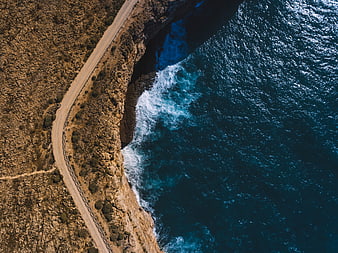 Aerial View of Winding Coastal Road and Deep Blue Ocean