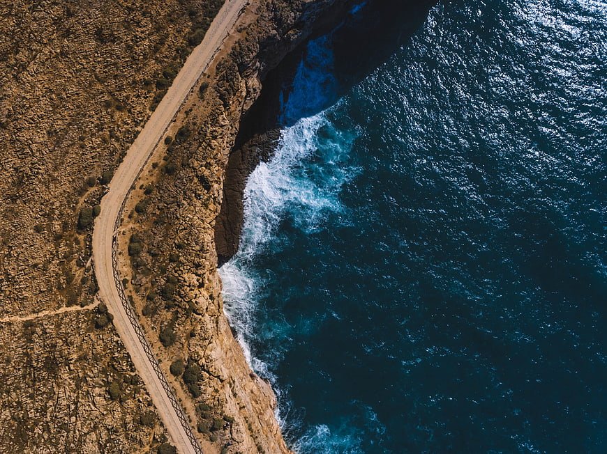 Aerial View of Winding Coastal Road and Deep Blue Ocean
